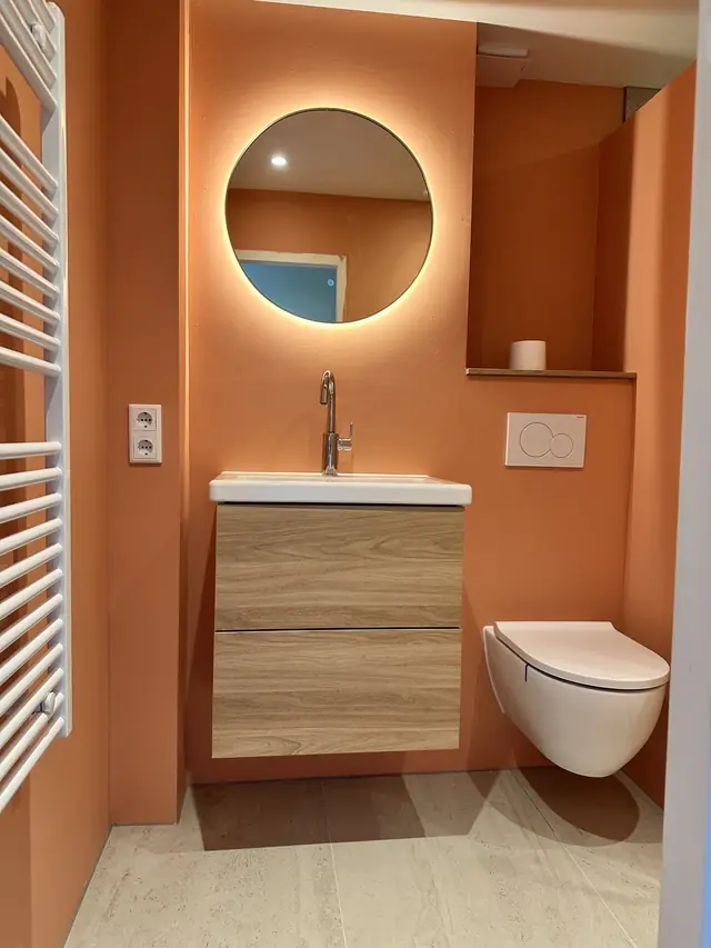 Compacte badkamer met warme accentwand, foto 1 van 7