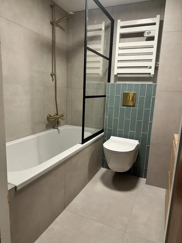 Badkamer met ligbad en groene tegelwand, foto 1 van 7