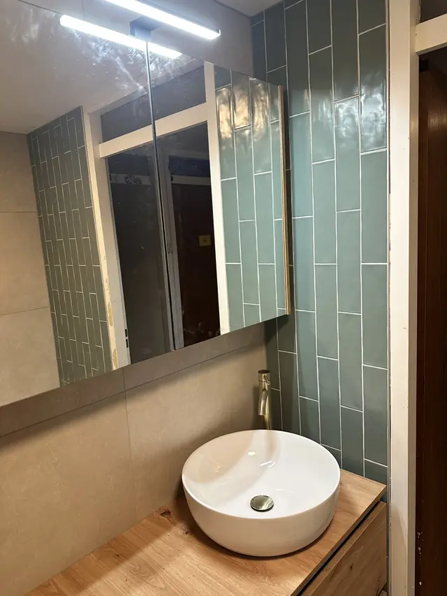 Badkamer met ligbad en groene tegelwand, foto 6 van 7