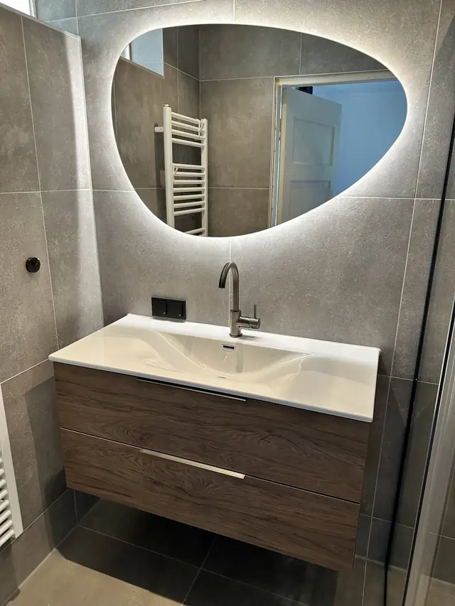 Badkamer in betonlook met verlichte spiegel, foto 1 van 10